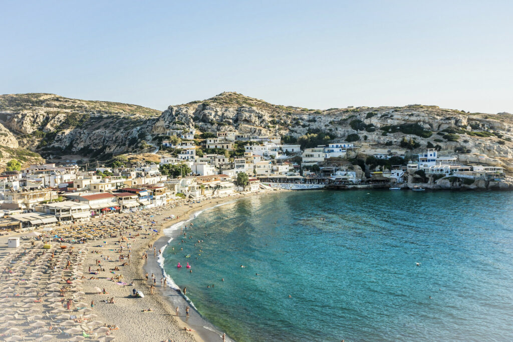 Best 10 Beaches in Crete, Greece Matala Beach cove with cliffside village and umbrella-lined sand, Crete