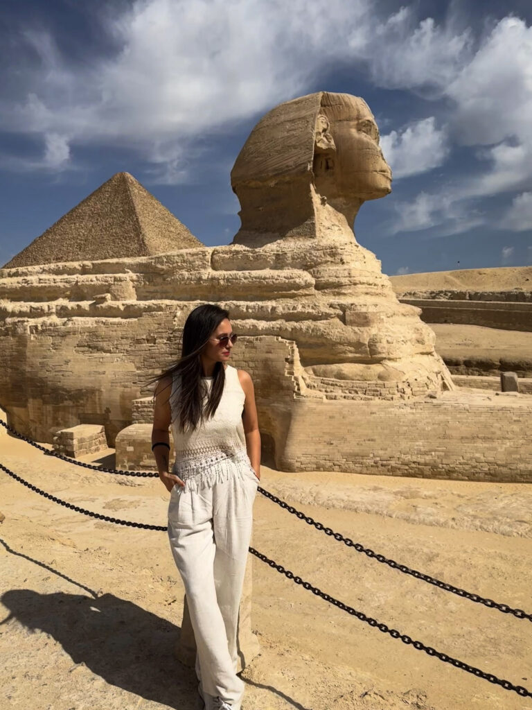3 Days in Cairo, Egypt Female traveler looking away with the ancient Sphinx monument and a Giza pyramid behind her under a blue sky