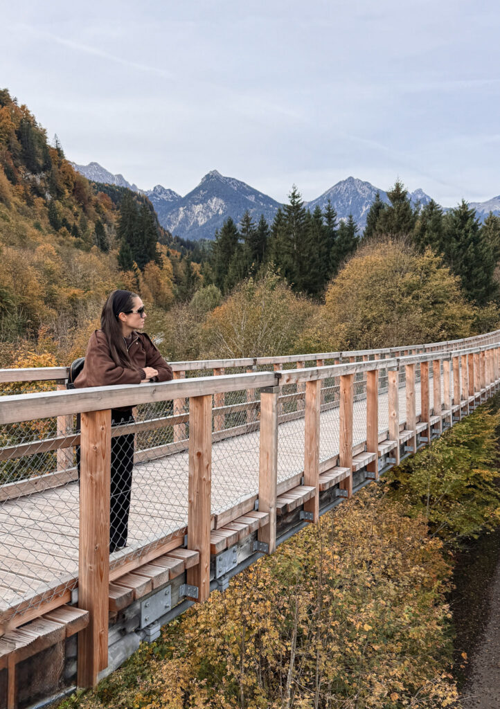 3 Days in Bavaria, Germany Traveler leaning on the wooden railing of Highline179 suspension bridge looking at autumn mountains
