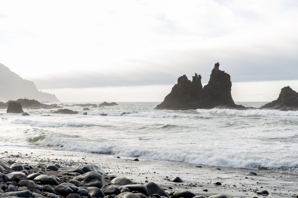 Top 10 Beaches in Tenerife Ocean waves washing over the rocky black sand shoreline of Playa de Benijo in northern Tenerife
