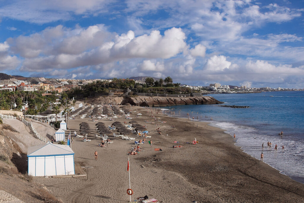 Top 10 Beaches in Tenerife Rows of thatched beach umbrellas and sunbeds on the sandy shores of Playa del Duque in Costa Adeje, Tenerife
