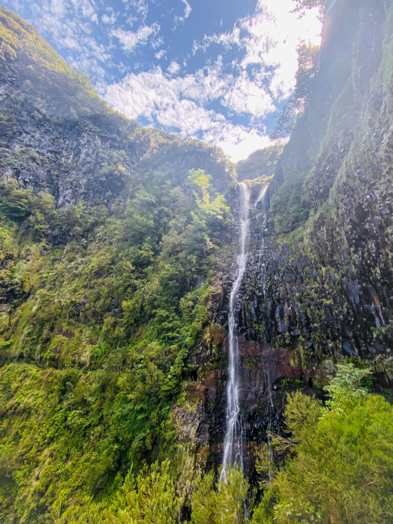 Madeira Travel Guide The towering Cascata do Risco waterfall plunging down a steep volcanic cliff covered in lush green vegetation in Madeira, Portugal.