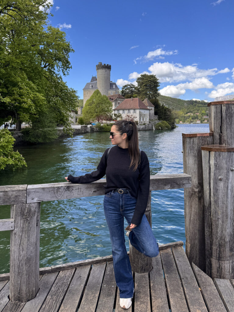Top 10 Places in Southeastern France Traveler posing on a wooden dock with the historic Château de Duingt and Lake Annecy in the background