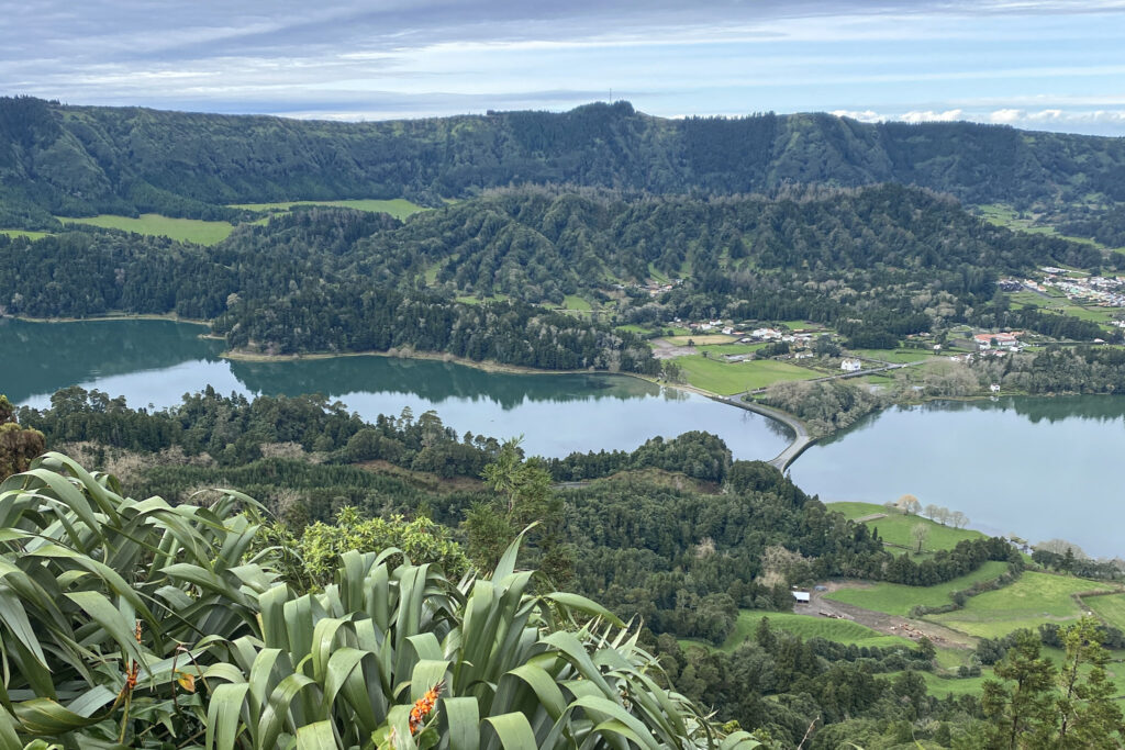 Top Things to Do in São Miguel, Azores Elevated view of the Sete Cidades twin lakes and a narrow bridge dividing them, framed by vibrant green foliage and volcanic crater walls in São Miguel, Azores.