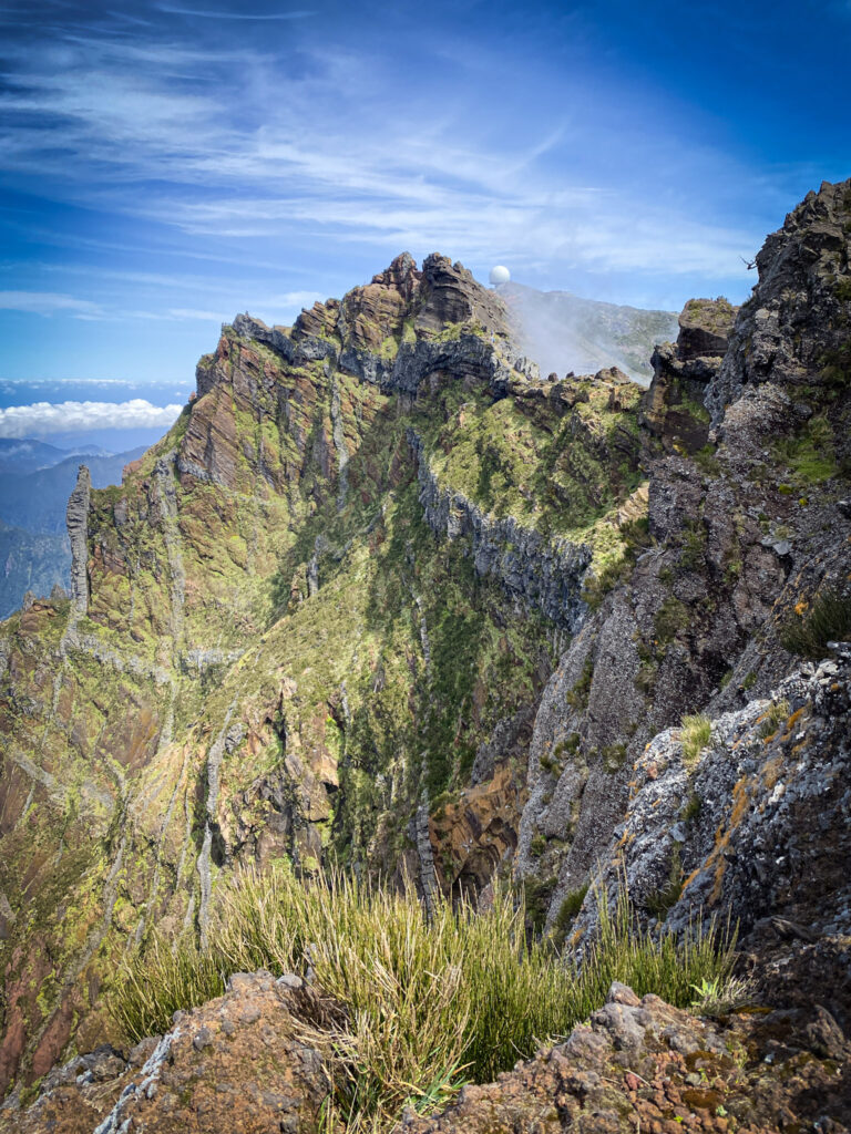 Madeira Travel Guide Dramatic sharp mountain peaks and rugged ridges along the PR1 Vereda do Arieiro trail under a blue sky in Madeira, Portugal.