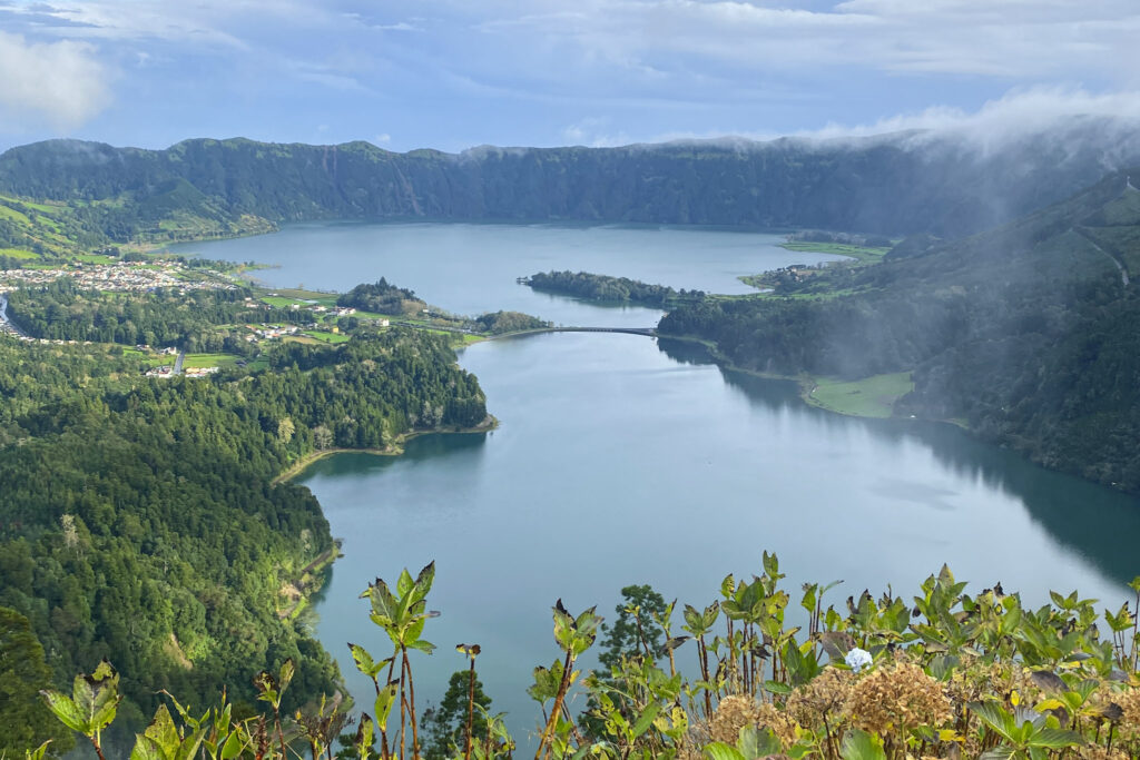 Top Things to Do in São Miguel, Azores Panoramic view of the volcanic crater lakes, Lagoa Azul and Lagoa Verde, surrounded by steep green mountains under a cloudy sky in Sete Cidades, São Miguel, Azores.