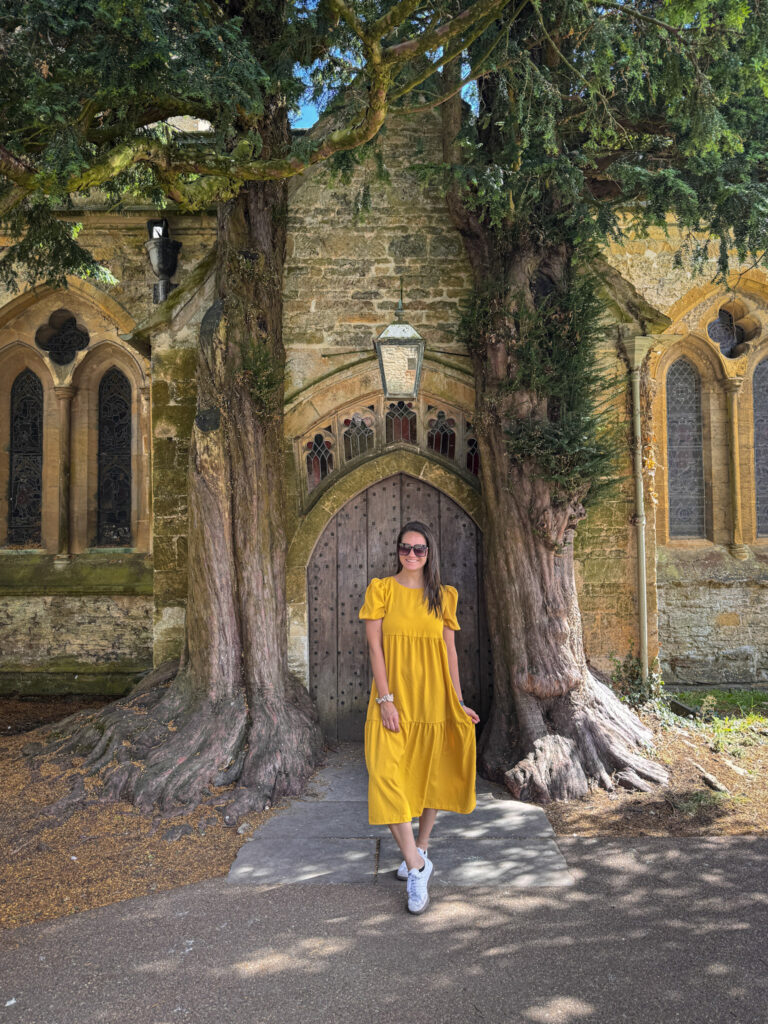Top 5 Villages in the Cotswolds A traveler standing before the iconic, ancient yew tree portal at St. Edward's Church in Stow-on-the-Wold.