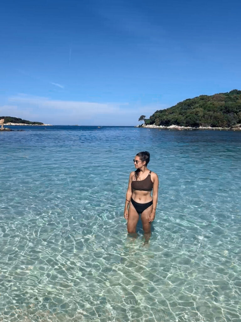 Top 10 Beaches in Ksamil, Albania Standing in crystal-clear turquoise sea water overlooking the green Ksamil Islands in Albania.