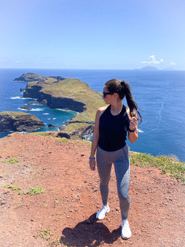 Madeira Travel Guide Traveler standing on a red dirt path overlooking the dramatic volcanic peninsula and blue ocean of Ponta de São Lourenço, Madeira.