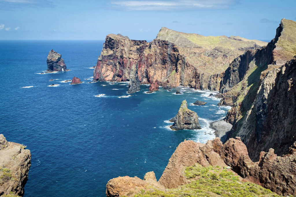 Madeira Travel Guide Panoramic view of the red and brown volcanic cliffs and sea stacks of Ponta de São Lourenço in Madeira.