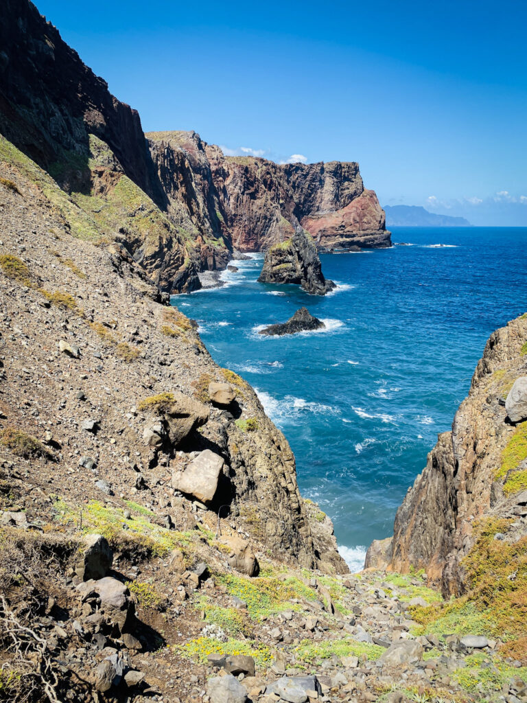 Madeira Travel Guide Rugged coastal cliffs and rock formations stretching into the blue Atlantic Ocean under a clear sky along the Madeira coastline.