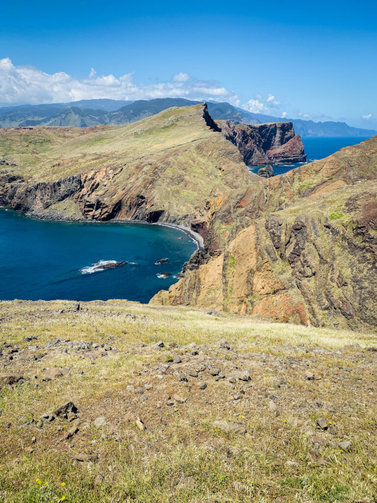 Madeira Travel Guide Panoramic view of sweeping volcanic ridges and colorful cliffs meeting a deep blue ocean bay at Ponta de São Lourenço, Madeira.